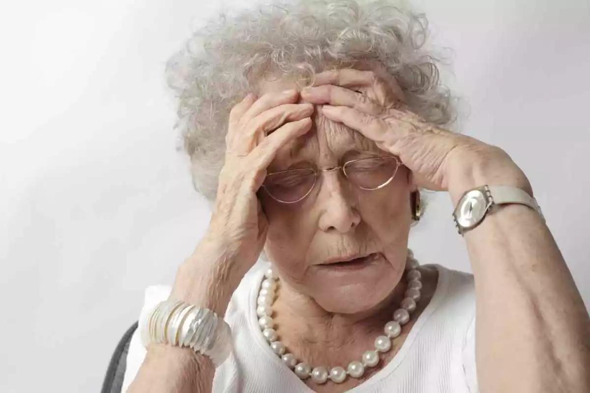Una anciana se pone las manos en la cabeza expresando indignación