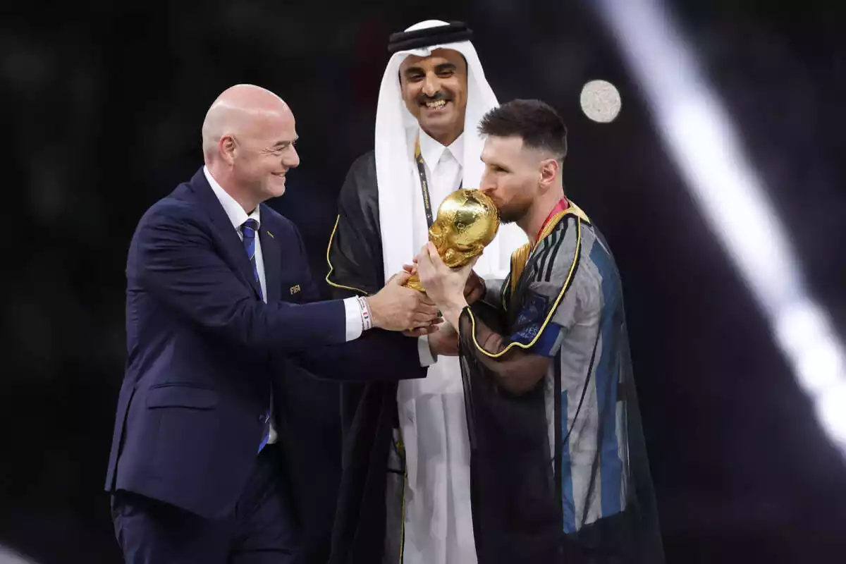 El jeque Tamim ben Hamad Al Thani sonríe y mira cómo Leo Messi besa la Copa del Mundo, a manos del presidente de la FIFA, Gianni Infantino