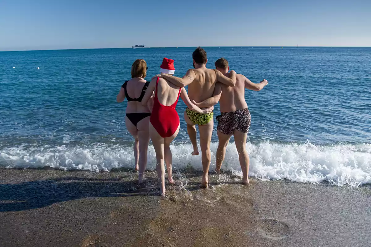 Unos jóvenes se bañan en la playa de la Barceloneta