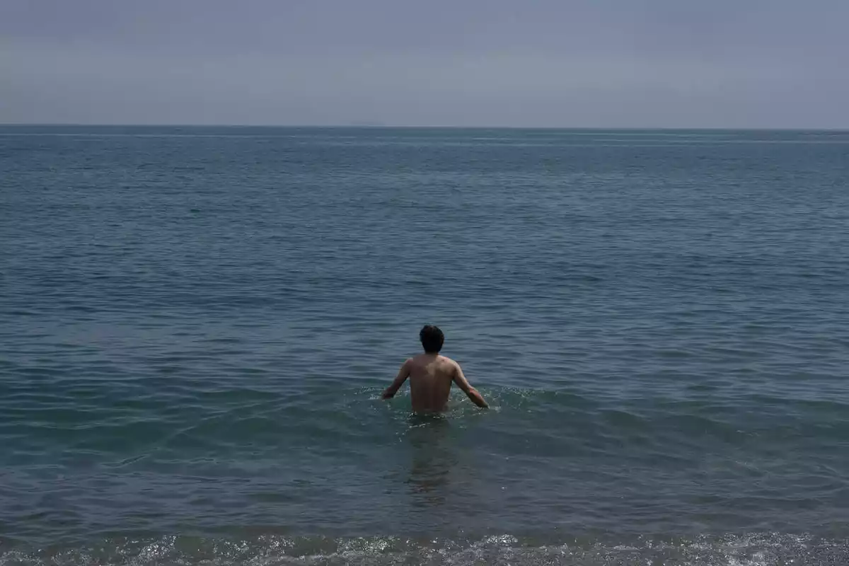 Un hombre se da un baño en la playa de la Barceloneta