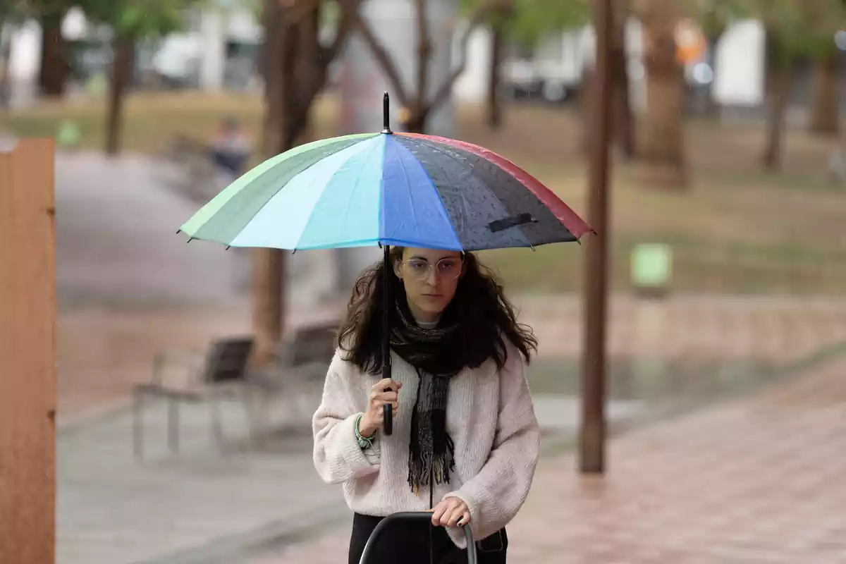 Una joven camina con un paraguas en Barcelona