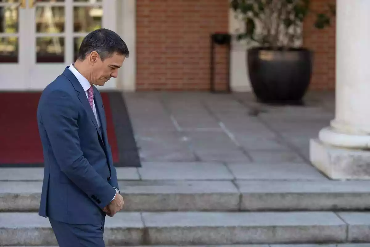 El presidente del Gobierno, Pedro Sánchez, mira hacia el suelo con las manos juntas