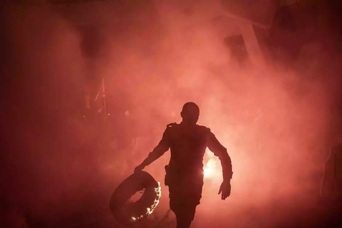 Un policía lleva un nivel en llamas durante una protesta en Jerusalén contra el gobierno religioso de derecha del primer Ministro Benjamin Netanyahu