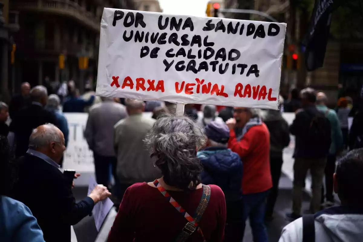 Una mujer sujeta un cartel de protesta durante una manifestación contra la privatización de la sanidad, a 7 de abril de 2024, en Barcelona
