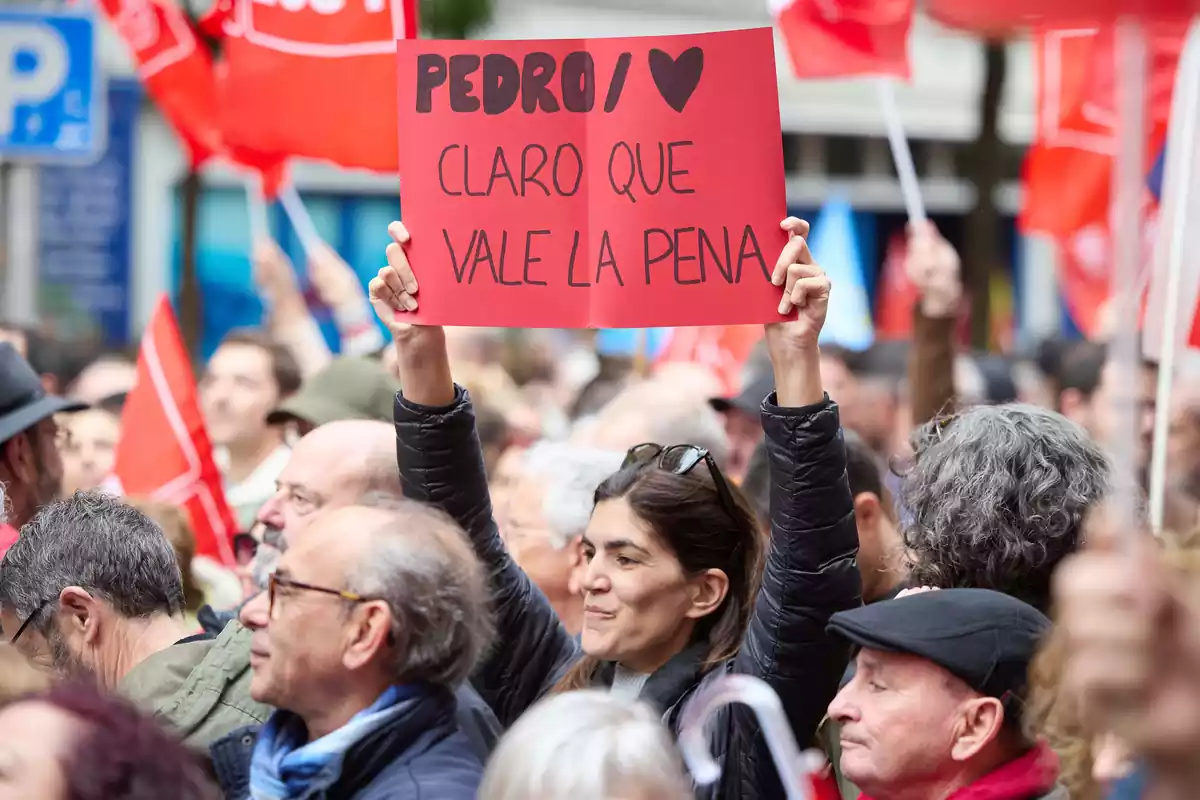 Una mujer sujeta un cartel durante una concentración en la calle de Ferraz en apoyo al presidente del Gobierno, Pedro Sánchez, en la sede del PSOE
