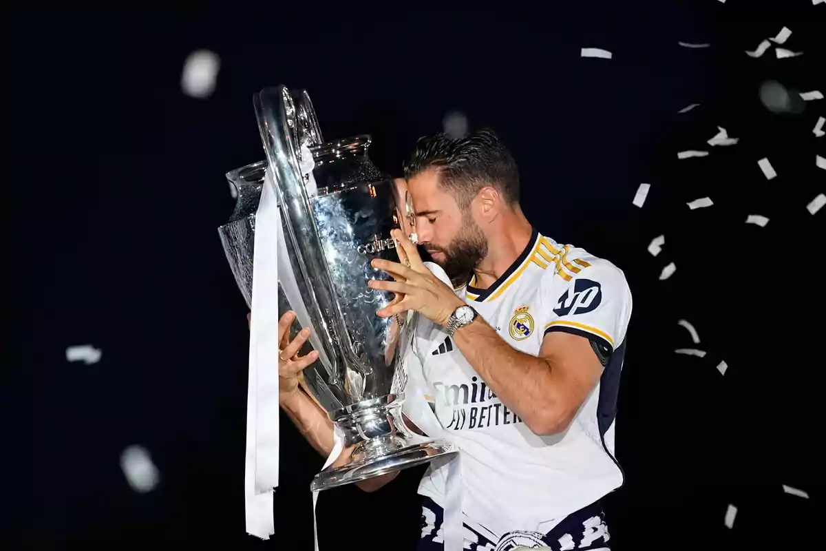 Jugador de fútbol del Real Madrid celebrando con el trofeo de la Liga de Campeones de la UEFA.