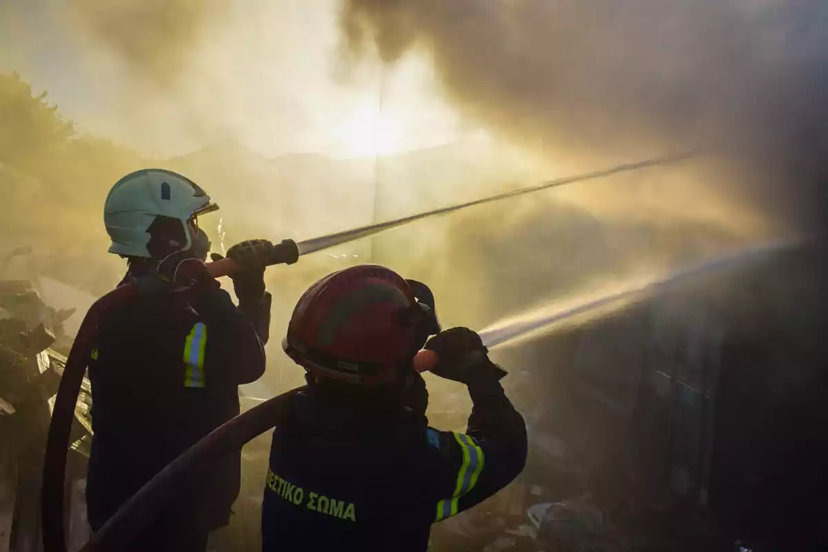 Bomberos combatiendo un incendio con mangueras de agua.