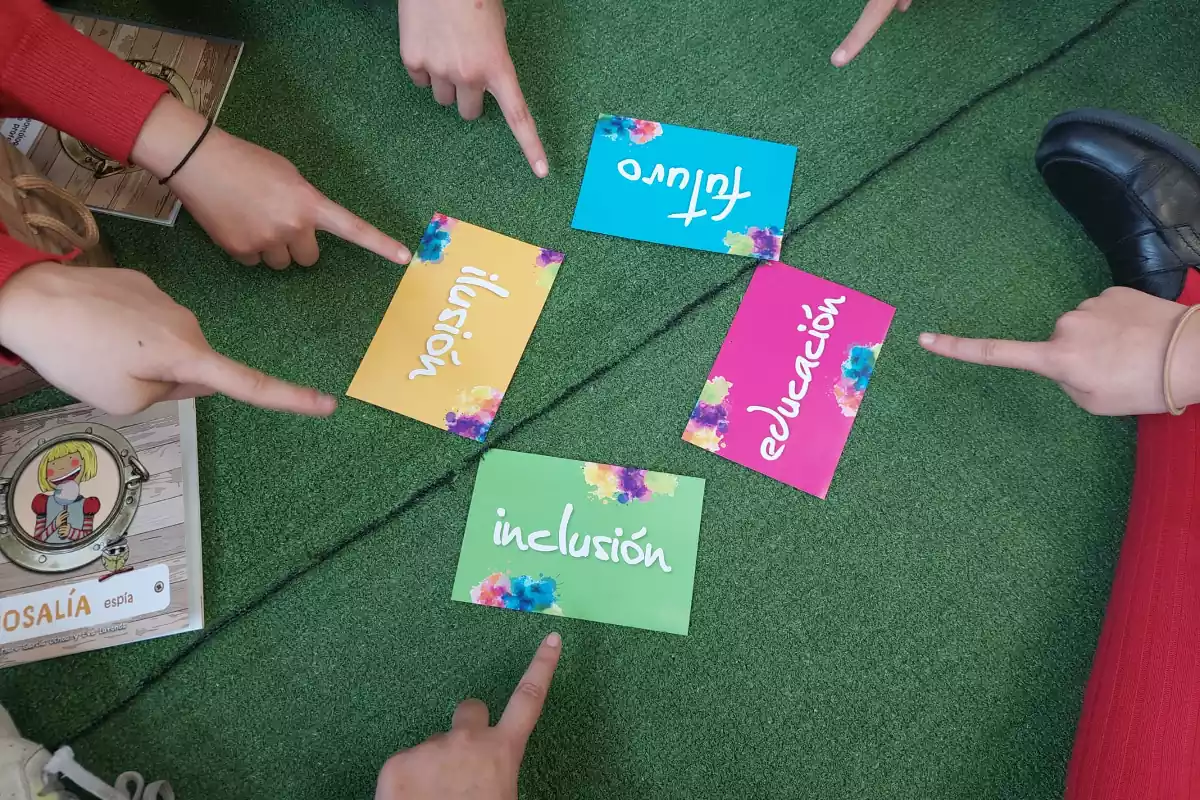 Niños indicando las cartas de inclusión, ilusión, futuro y educación