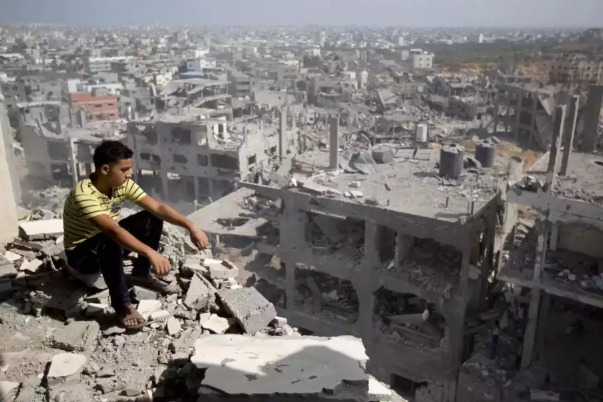Niño sentado frente a los escombros en una guerra