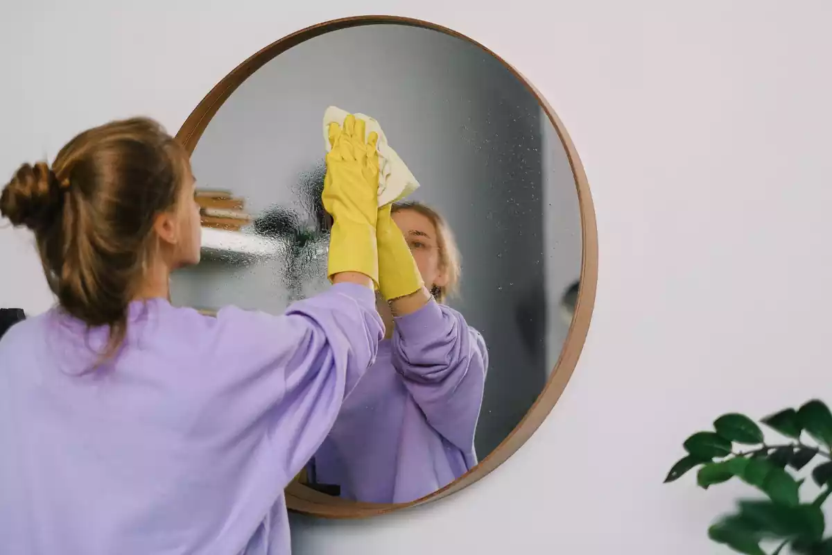 Una mujer limpiando un espejo